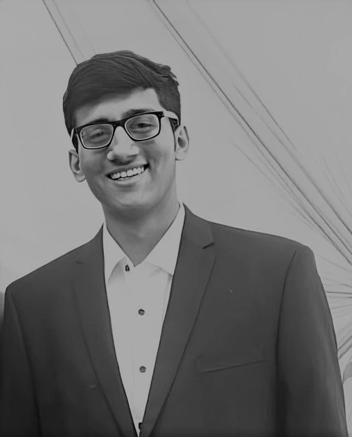 Sarthak Vala smiling, wearing glasses and a suit
